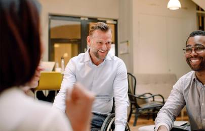 Disabled worker in wheelchair smiling with co-workers