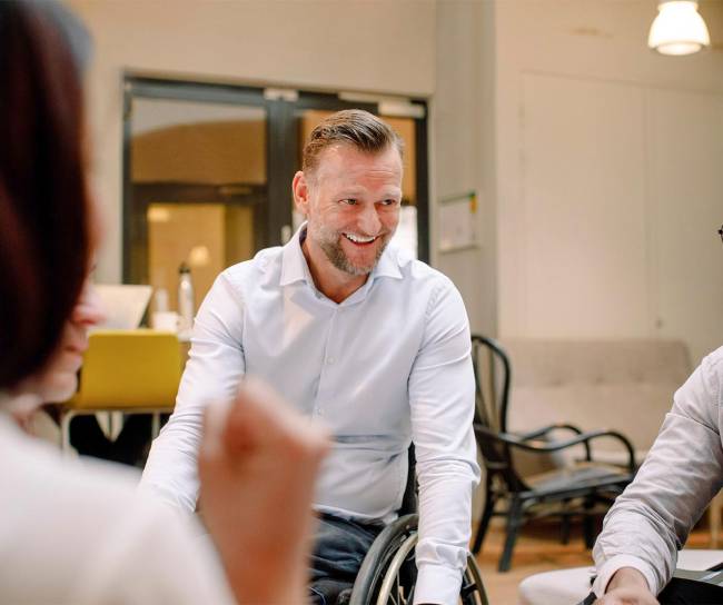 Disabled worker in wheelchair smiling with co-workers