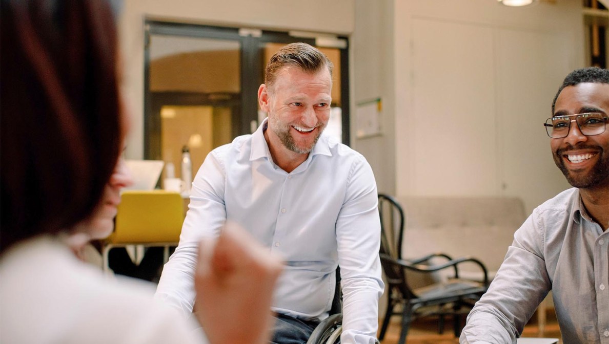 Disabled worker in wheelchair smiling with co-workers