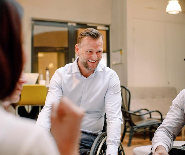 Disabled worker in wheelchair smiling with co-workers