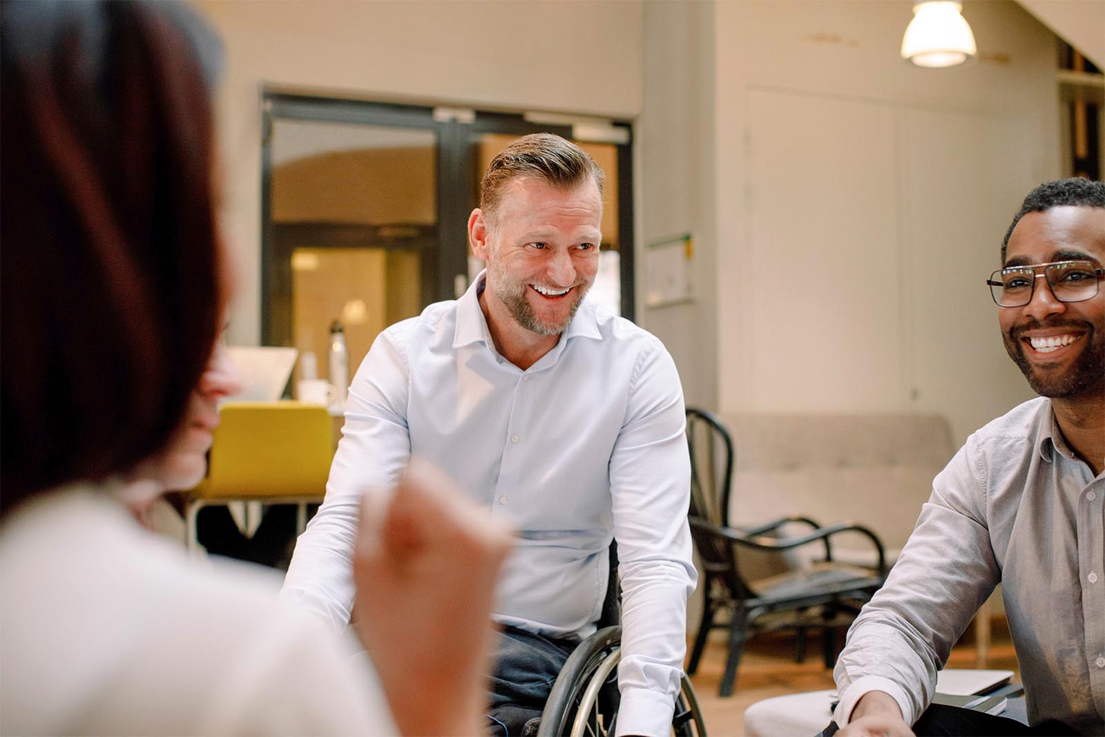 Disabled worker in wheelchair smiling with co-workers